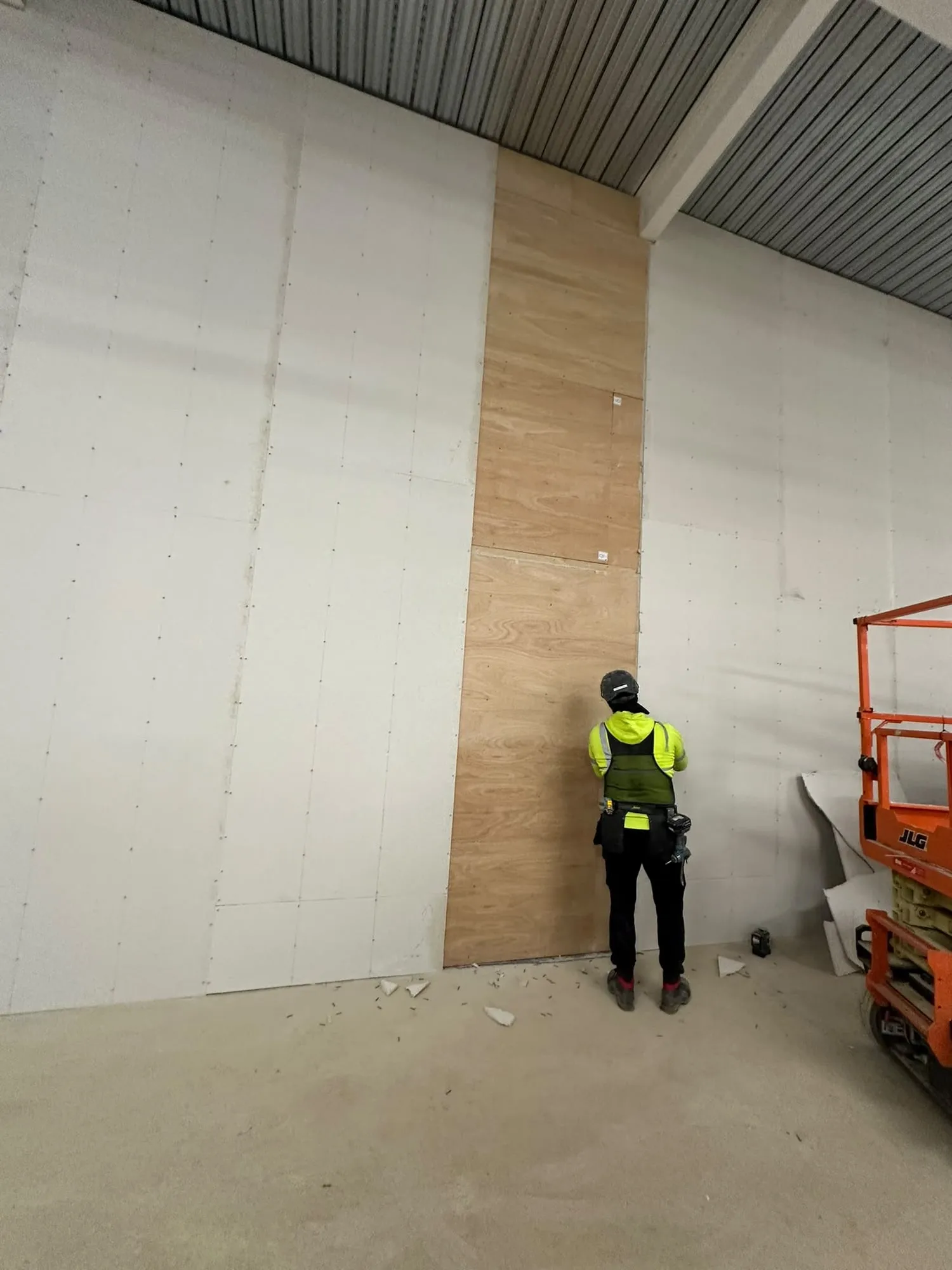 A tall wall boarded out in plasterboard, with one of our team at work