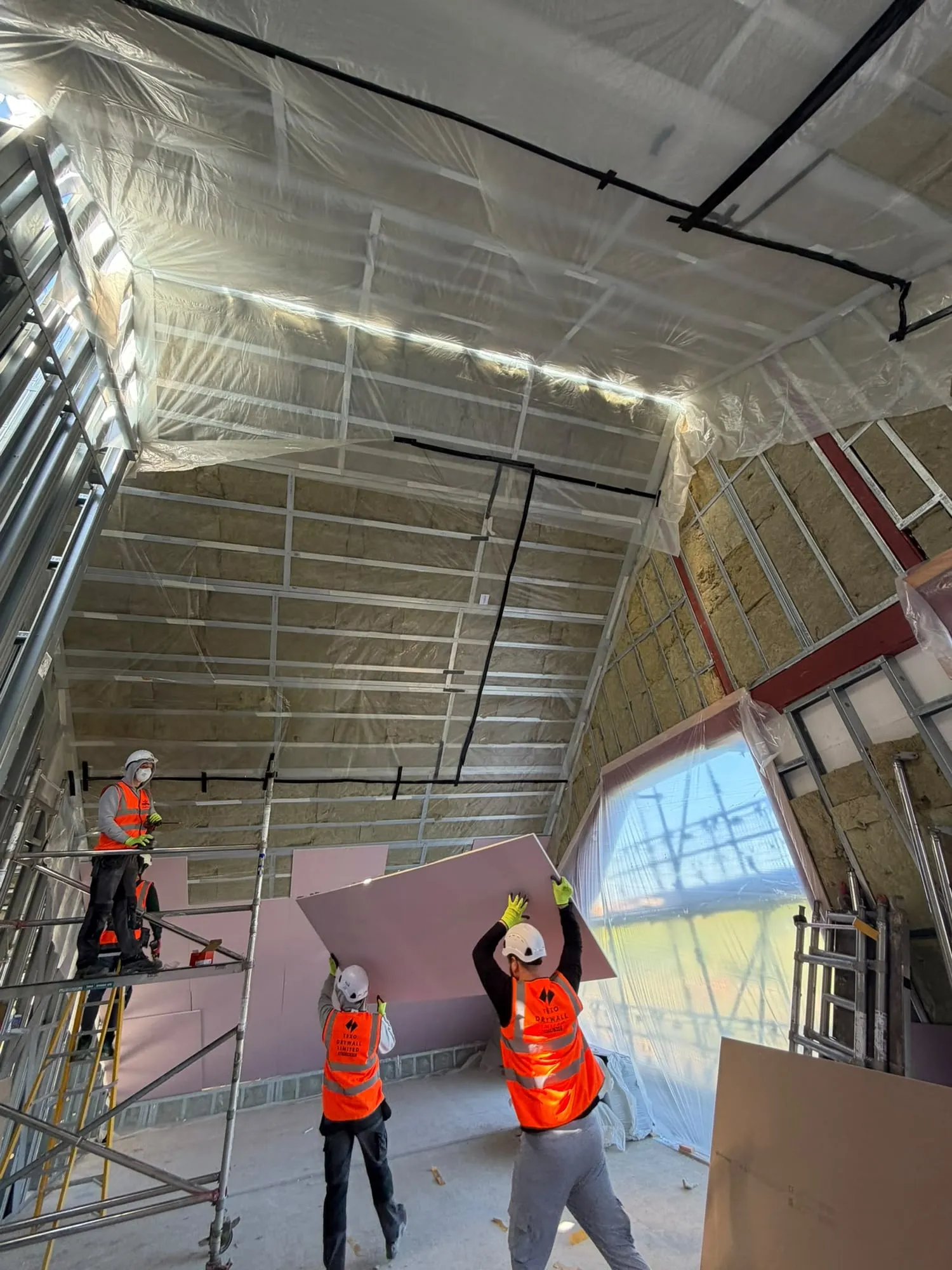 Our team lifting plasterboard onto a high insulated wall