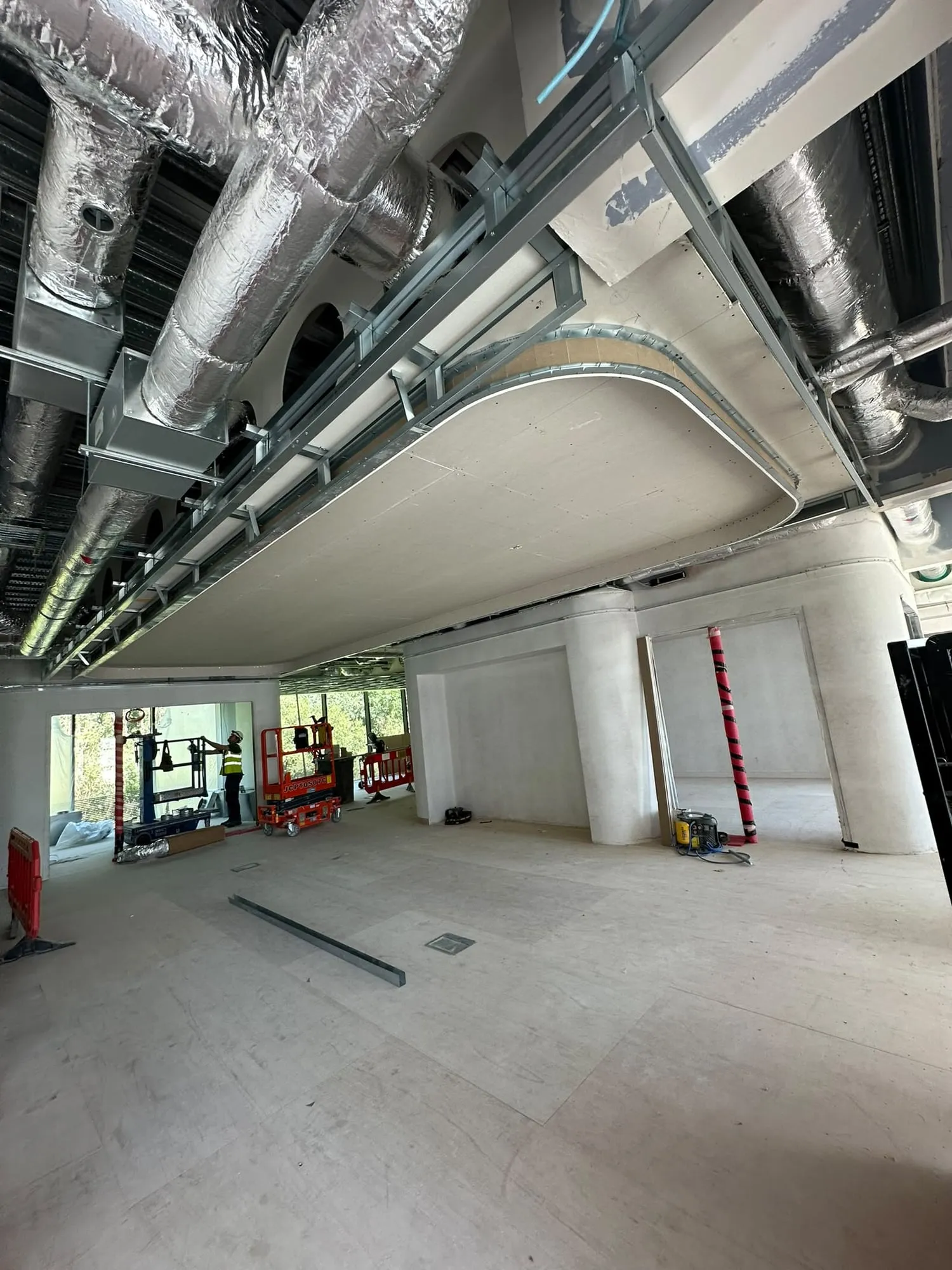 Curved plasterboard bulkhead under the service ducts on an open-plan floor