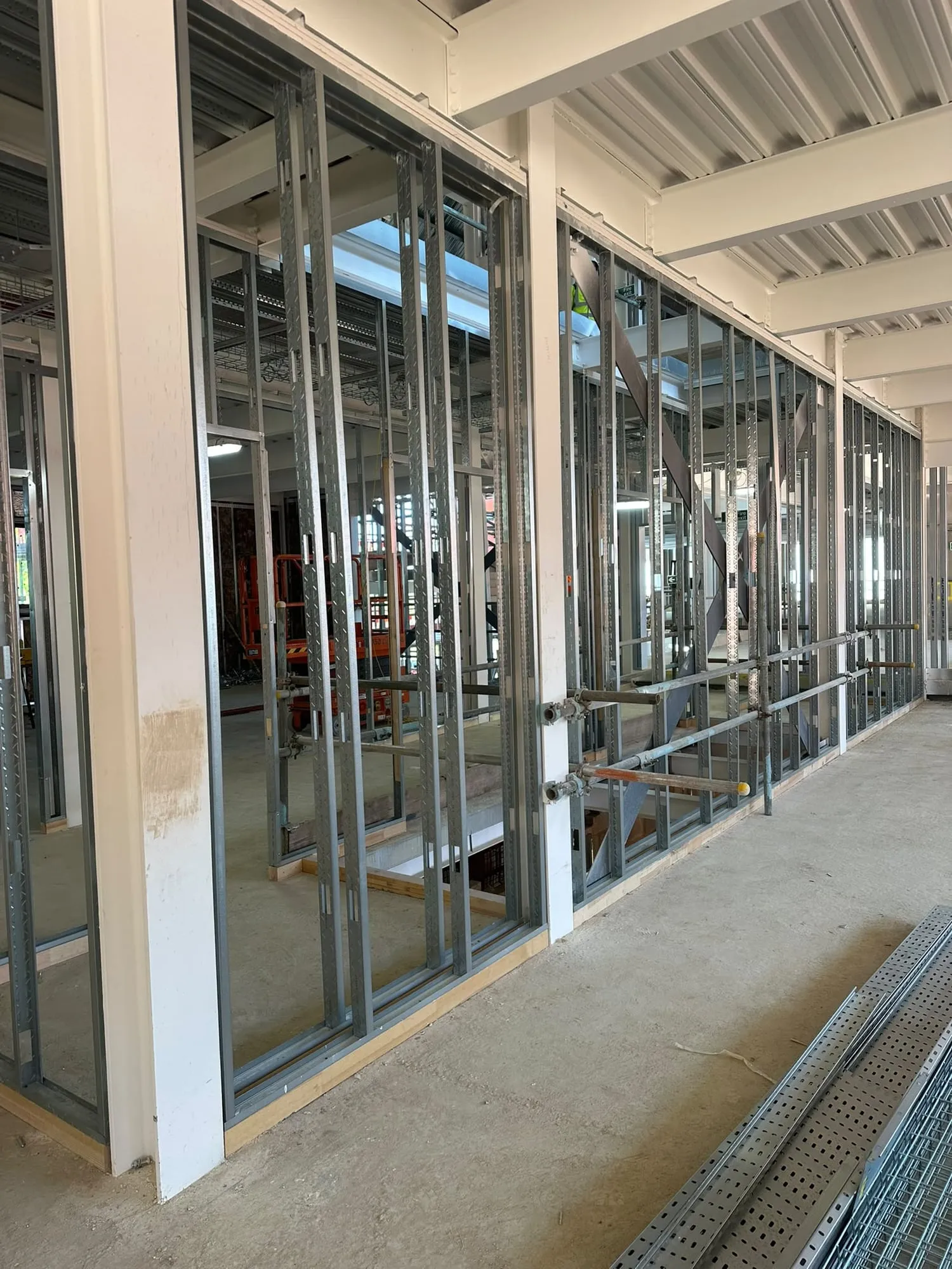 Metal framing for new walls along a glazed elevation